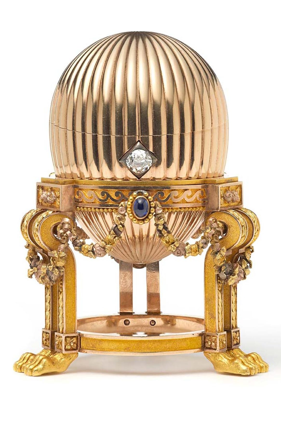 The image is a gold and diamond encrusted egg on a stand. The egg is decorated with intricate patterns and has a large diamond on the side. The stand is also decorated with gold and diamonds.
