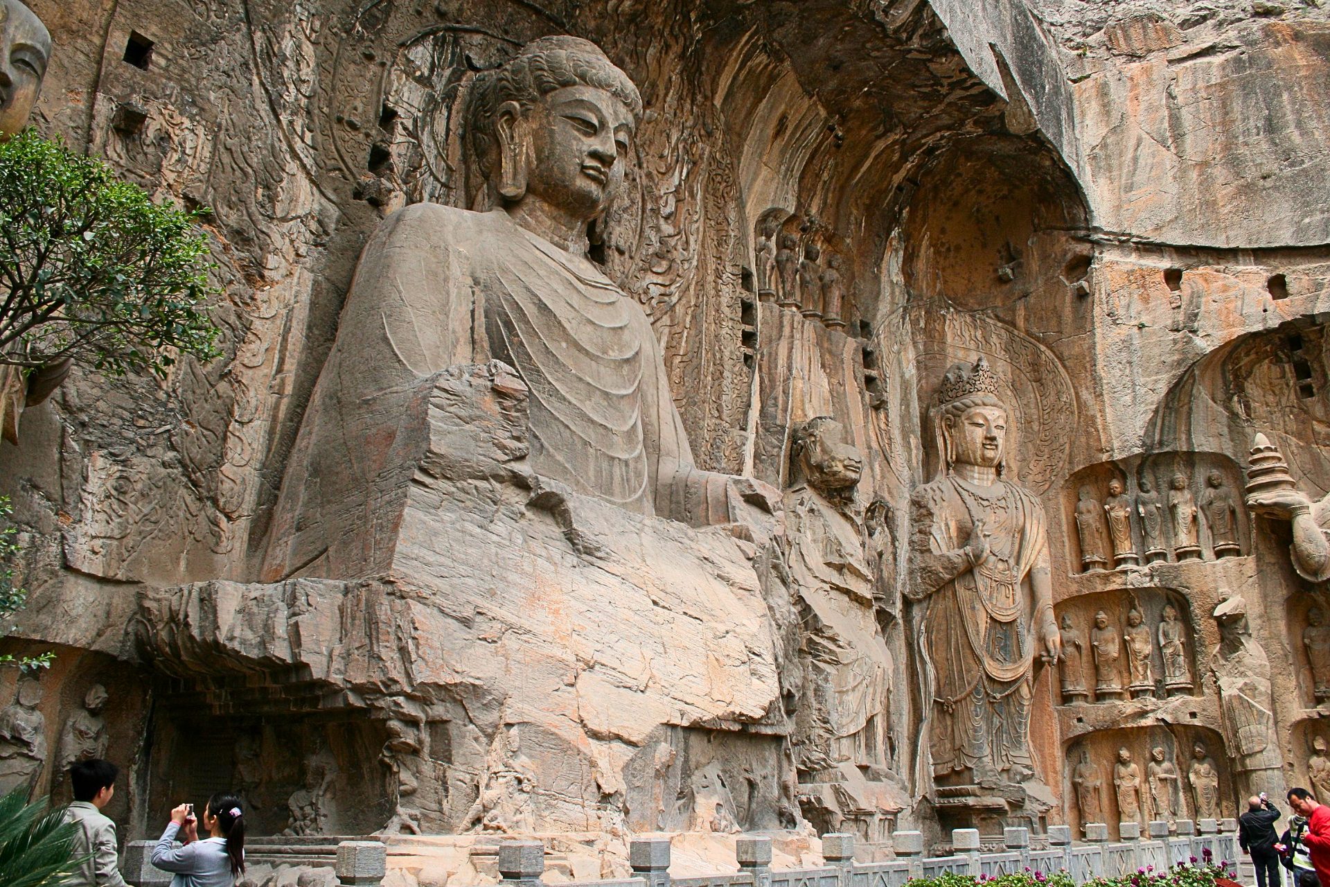 A photograph of large buddhist statues carved into the side of a mountain.