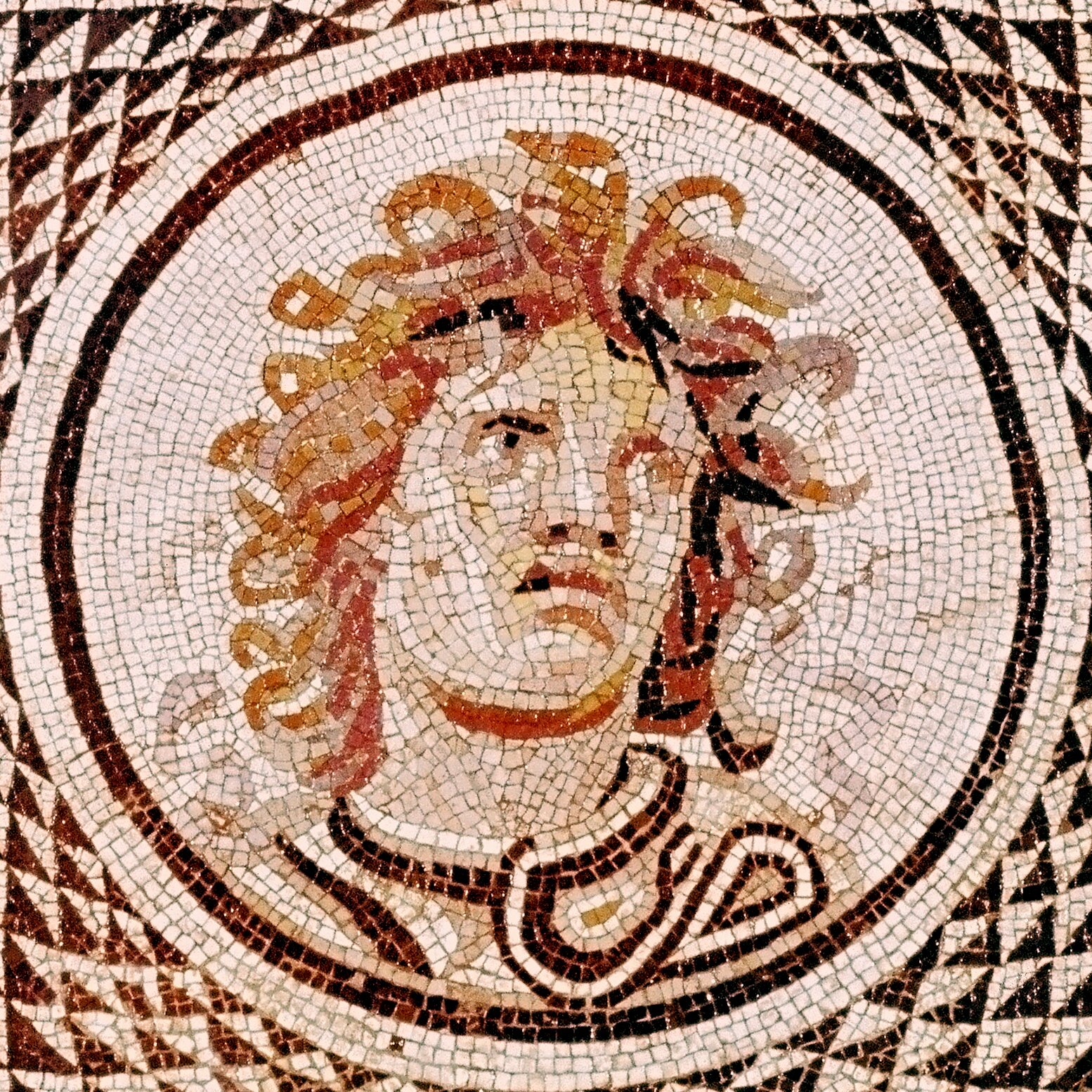A Roman mosaic floor features a more human-like Medusa bust from the 100s A.D., with wild curls instead of snake locks, and traits resembling Alexander the Great. The mosaic positions Medusa within a shield of concentric circles, producing an optical illusion with alternating black and white triangles.