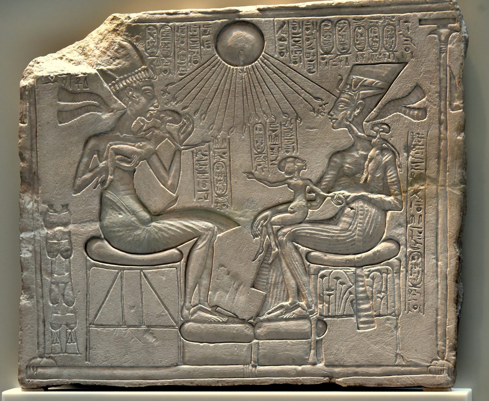 Egyptian stone carving showing the sun shining on the king, the queen and their three daughters