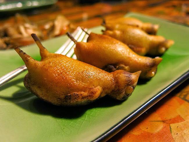 A photograph featuring three small fried birds on a green plate.