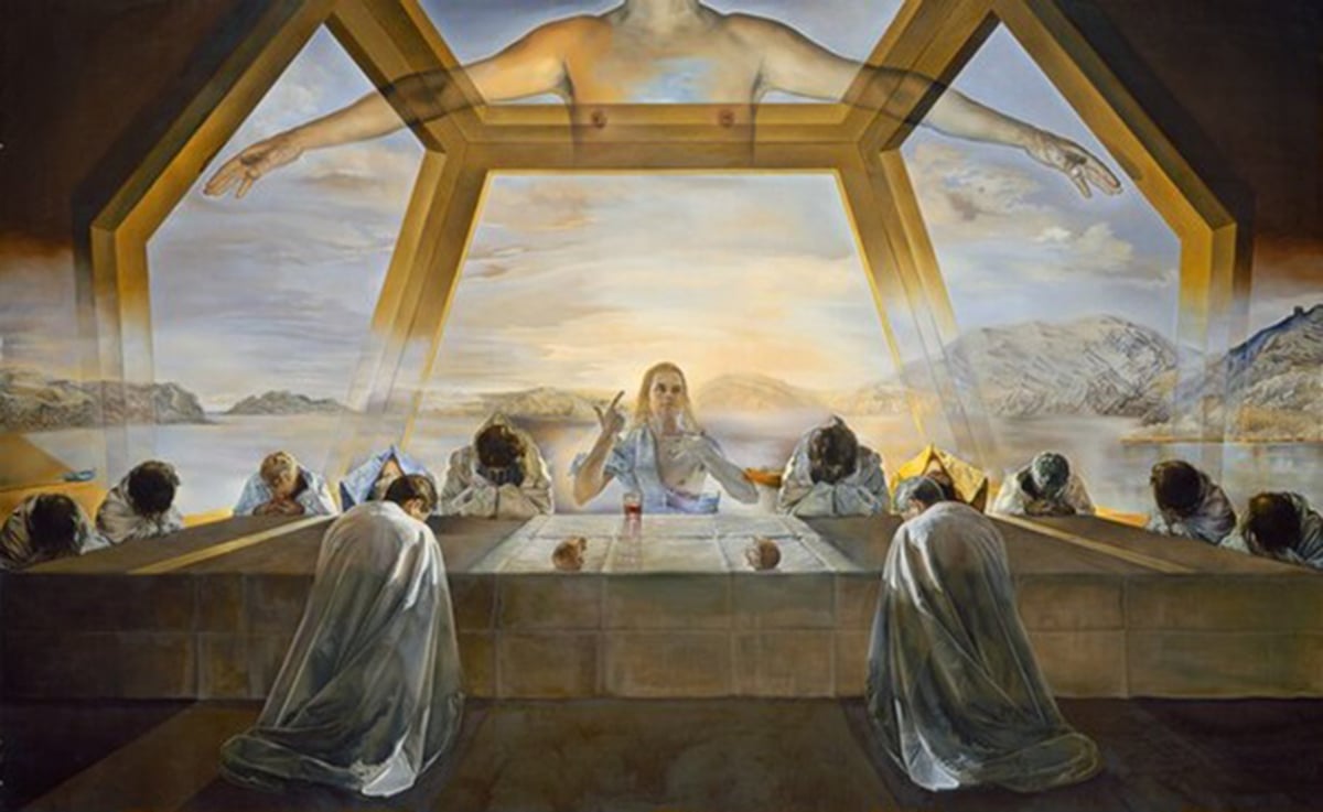 A surreal painting of the Last Supper scene, with Jesus and his twelve apostles gathered around a long table. Jesus is the central figure, wearing a white robe and pointing upwards. Above him, a transparent torso of a man with arms outstretched spans the width of the painting, representing God the Father. The table is set with bread, wine, and a lamb. The apostles are dressed in white cloaks and have identical faces and hairstyles, except for Judas, who is turned away from Jesus and has a dark beard. The background is a landscape of the Catalan coast, with cliffs, water, and a blue sky. The painting is based on mathematical ratios and symbols, such as the dodecahedron shape of the room and the pentagonal windows.