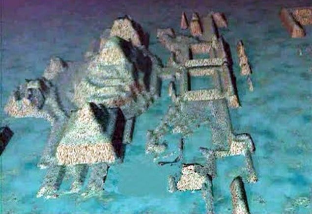 The image shows an underwater scene with ruins of a city on the bottom of the ocean. Several large pyramids can be seen in the city. The ruins appear to be made of stone.