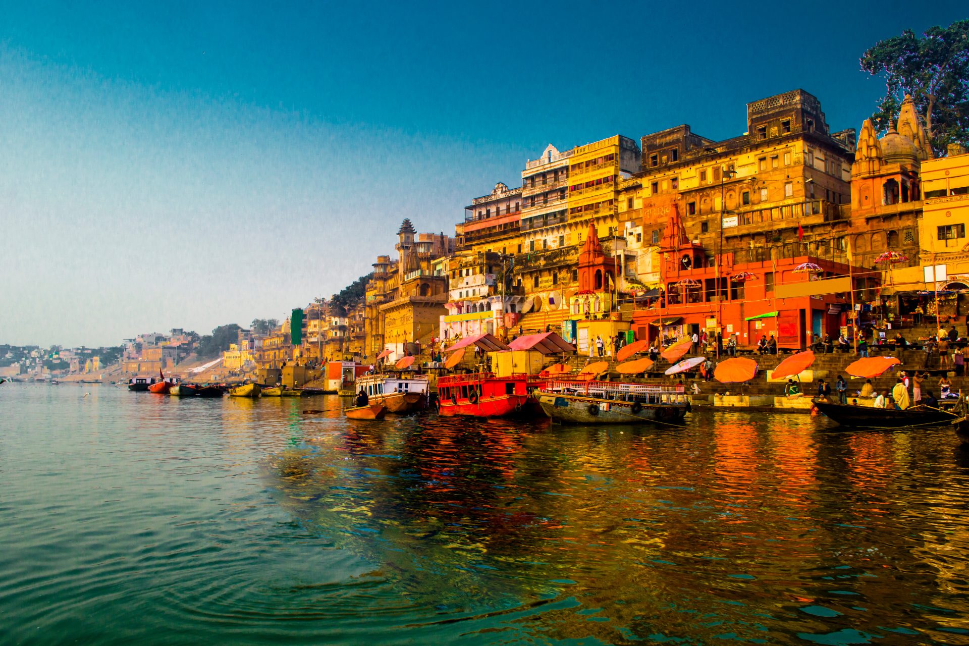 A photograph of building along the riverbank in Varanasi, India taken at sunrise.