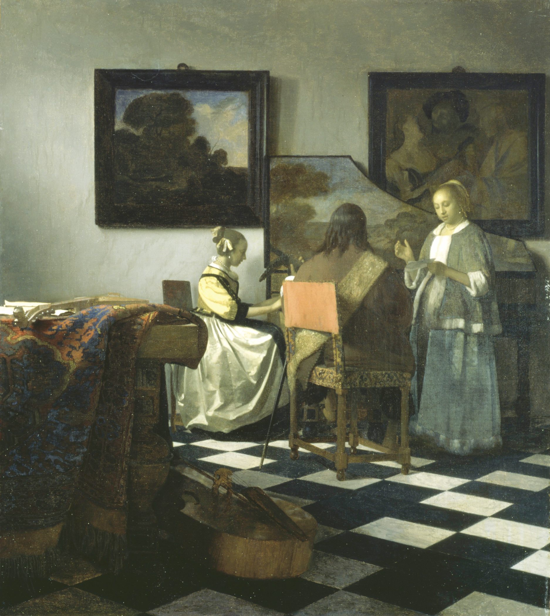 A painting of a room with a checkered floor, a woman is sitting at a grand piano, a man sits next to her. He seems to be a music instructor. Next to them there is another woman standing, she appears to be singing. There are paintings on the wall behind them.