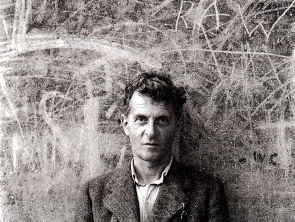 A photo of Ludwig Wittgenstein in front of a backboard.