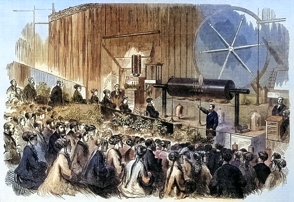 An illustration of Professor Pepper demonstrating the Great Electric Induction Coil at the Polytechnic Institution in London in 1869. The coil is a large cylindrical device that produces sparks of electricity. A crowd of people in Victorian clothing watches the experiment with curiosity and awe.