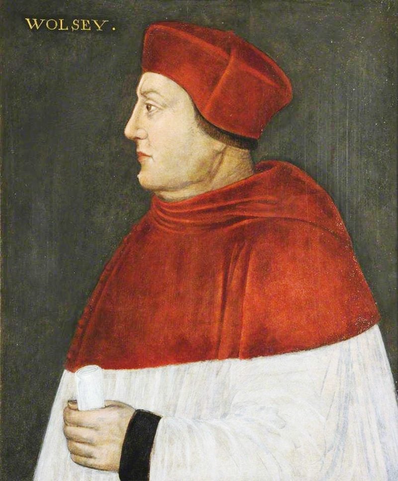 A side portrait of Cardinal Thomas Wolsey. He is dressed in red and white priestly robes and a red hat. A rolled up document is in his left hand.