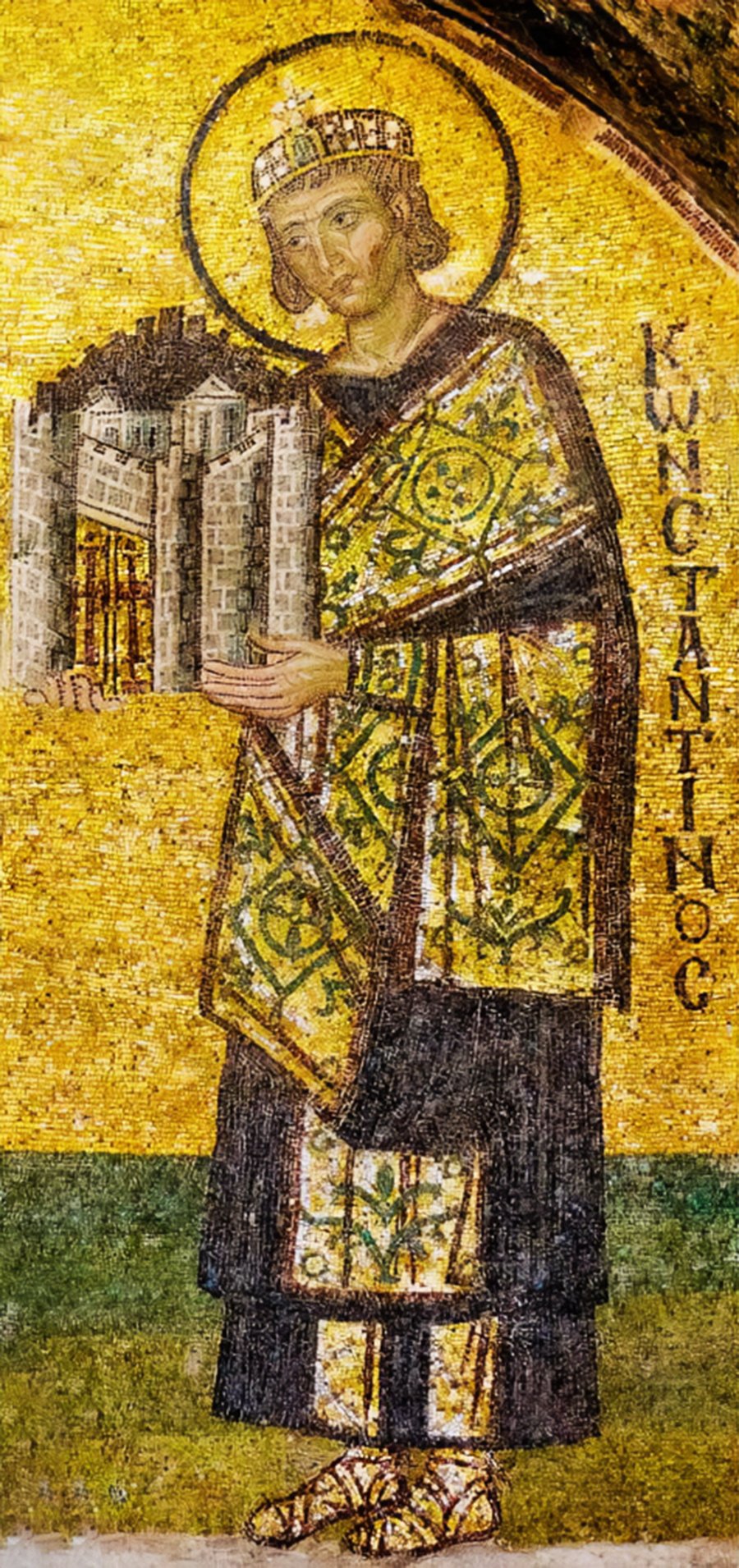 A mosaic of Emperor Constantine I holding a model of a church, with a yellow robe, a halo, a gold background, and the text “KWCANTIOC” in the top right corner.