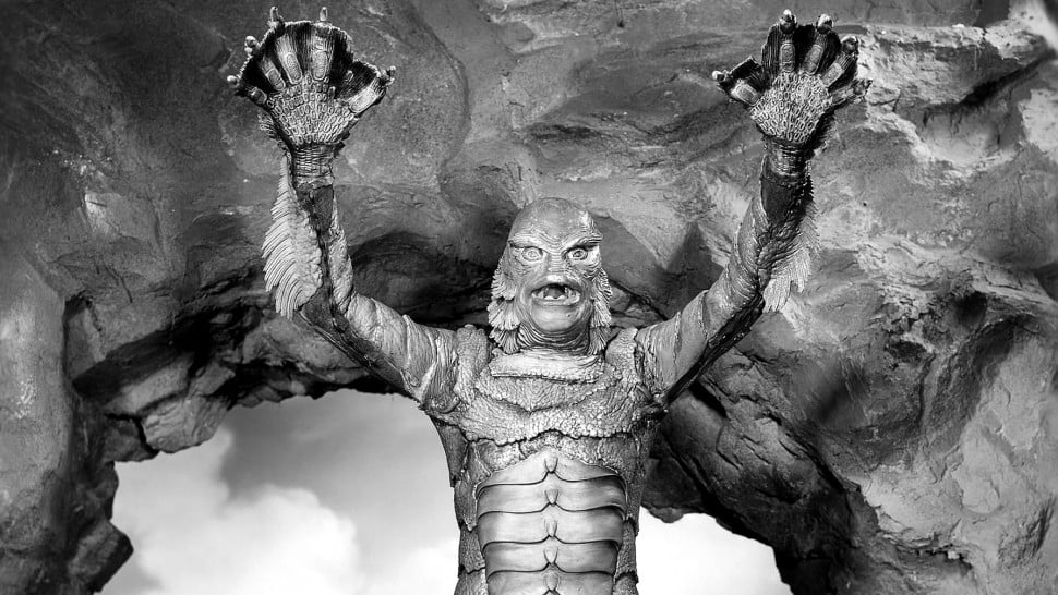 A still image of a humanoid sea monster raising its arms.