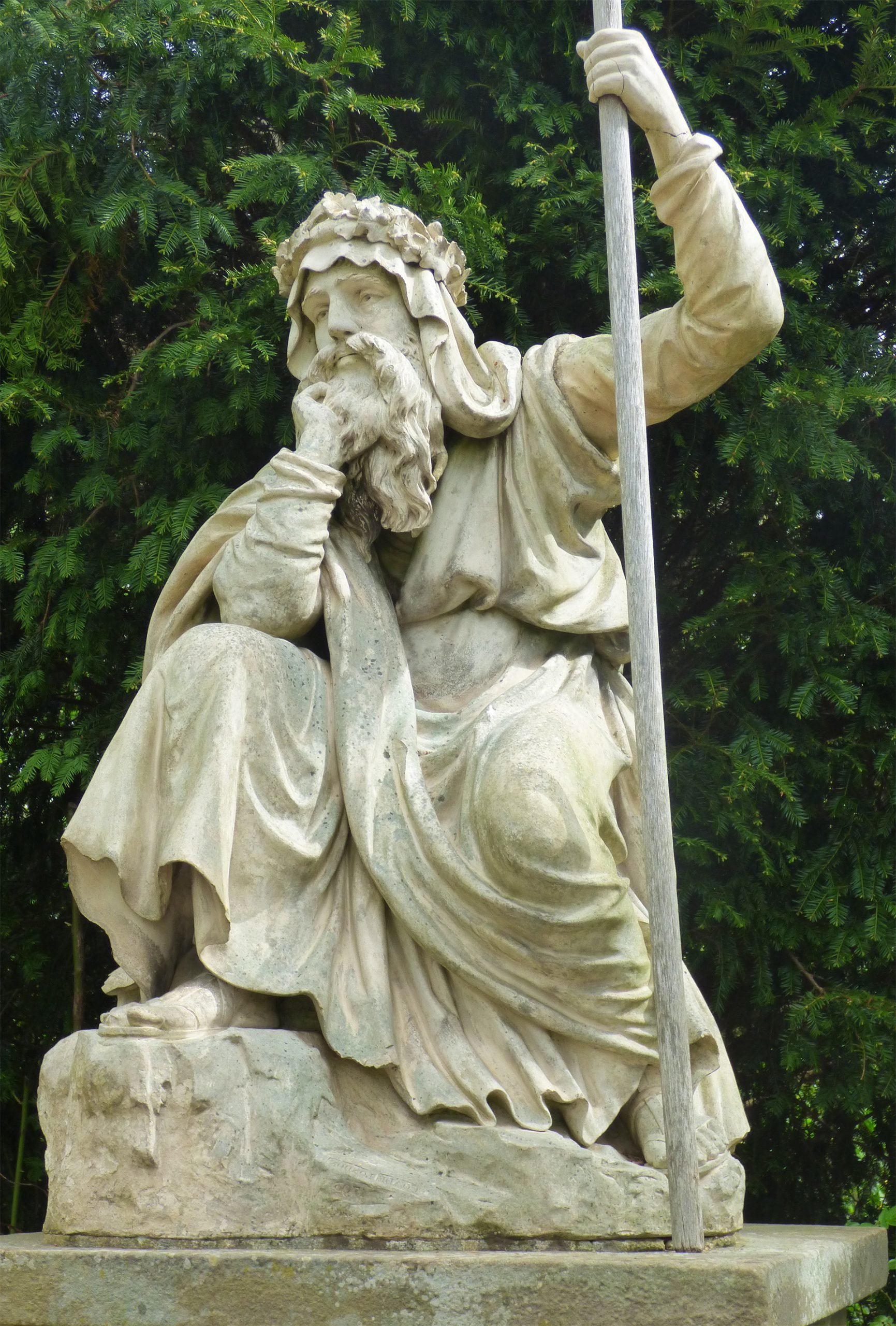 A statue of a druid situated in Croome Park, carved in detail, capturing the essence of druidic attire and posture, set against the backdrop of the park's natural landscape.