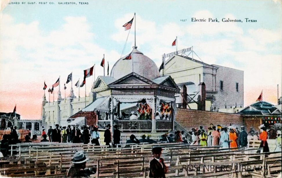 A postcard showing a large white building with a dome and flags on the roof, labeled "Electric Park". People are walking on the boardwalk in front of the building and a crowd is gathered at the entrance. The postcard is published by Gust. Feist, Galveston, Texas.