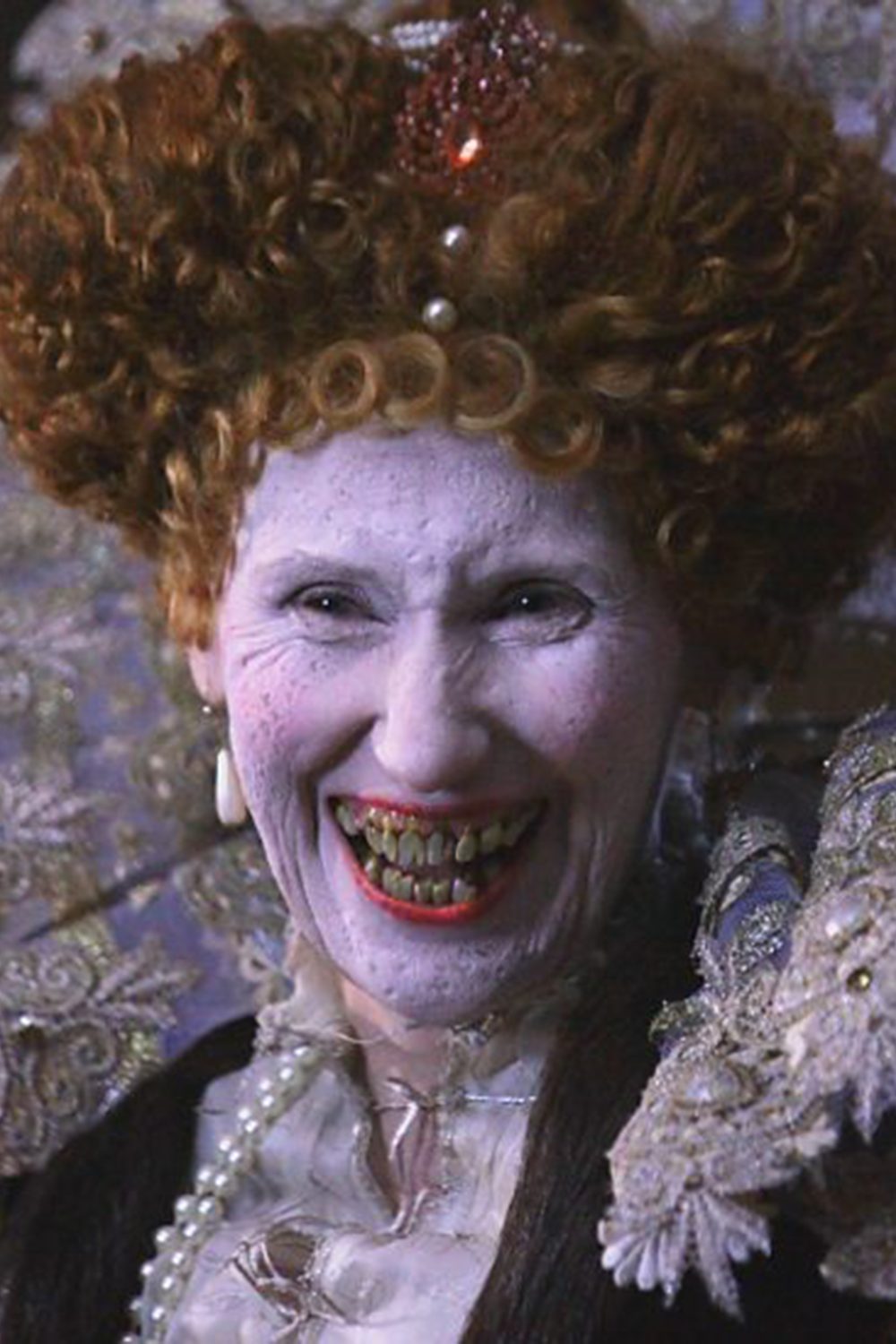 A still image from the film Armada: 12 Days to Save England featuring Queen Elizabeth I with white makeup, smallpox damaged skin and grotesquely rotten teeth.