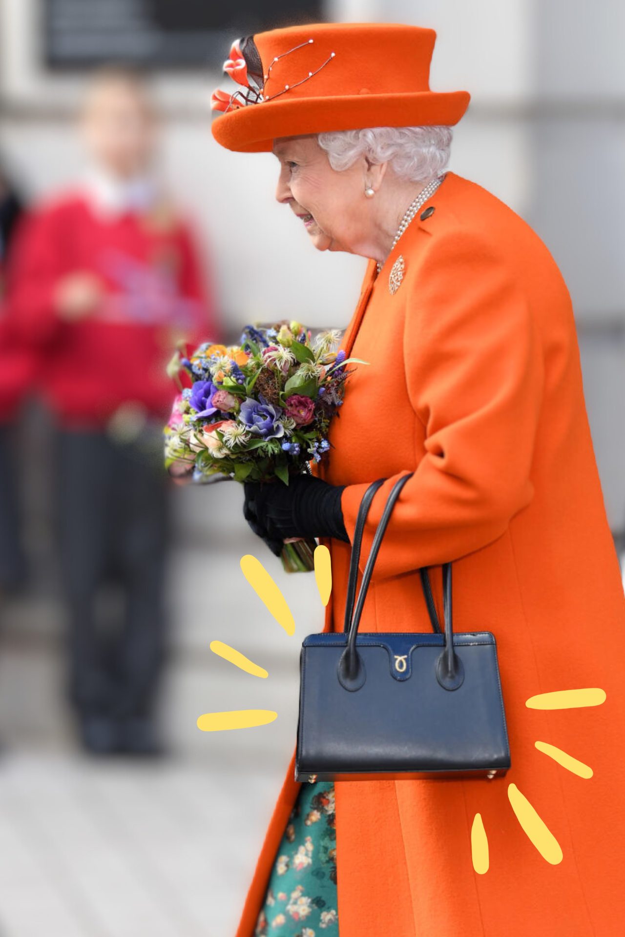 A photograph of Queen Elizabeth II, dressed in a red coat and a red hat. She is holding a bouquet and has a black handbag hanging off her arm.