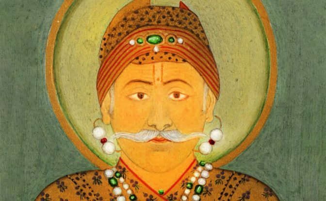 A portrait in opaque watercolor and gold on paper of Emperor Akbar, adorned in a gold outfit with a floral motif and an array of intricate jewelry.