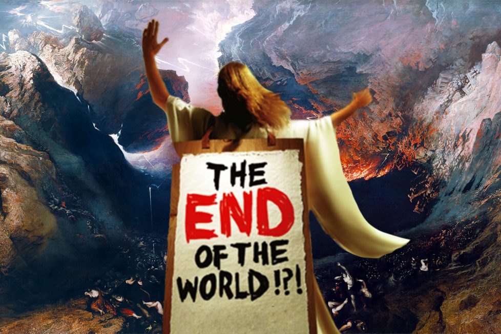 A person in a white robe stands on a cliff with their arms outstretched, a sign on their back says “THE END OF THE WORLD?!” in red and black letters. The background is a fiery landscape with smoke and fire. The image conveys a sense of apocalypse and drama.
