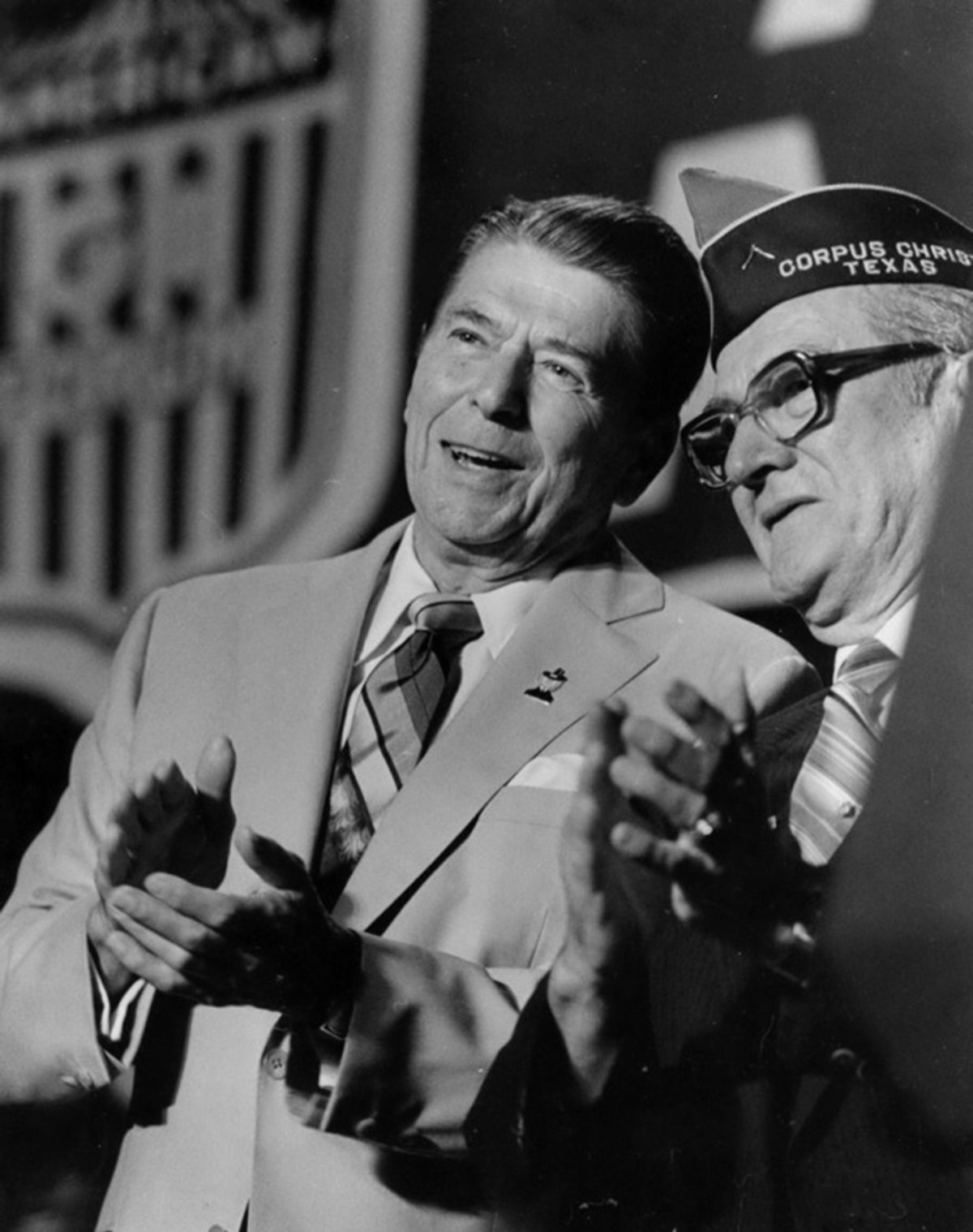 President Ronald Reagan at the American GI Forum alongside its founder, Hector Garcia. They are wearing suits and clapping.