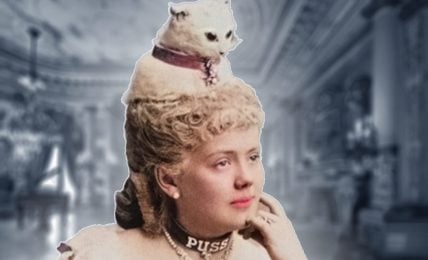 This image features a woman that is wearing a white fur cat on her head. She has long blond hair and dark eyes. She is wearing a white dress.