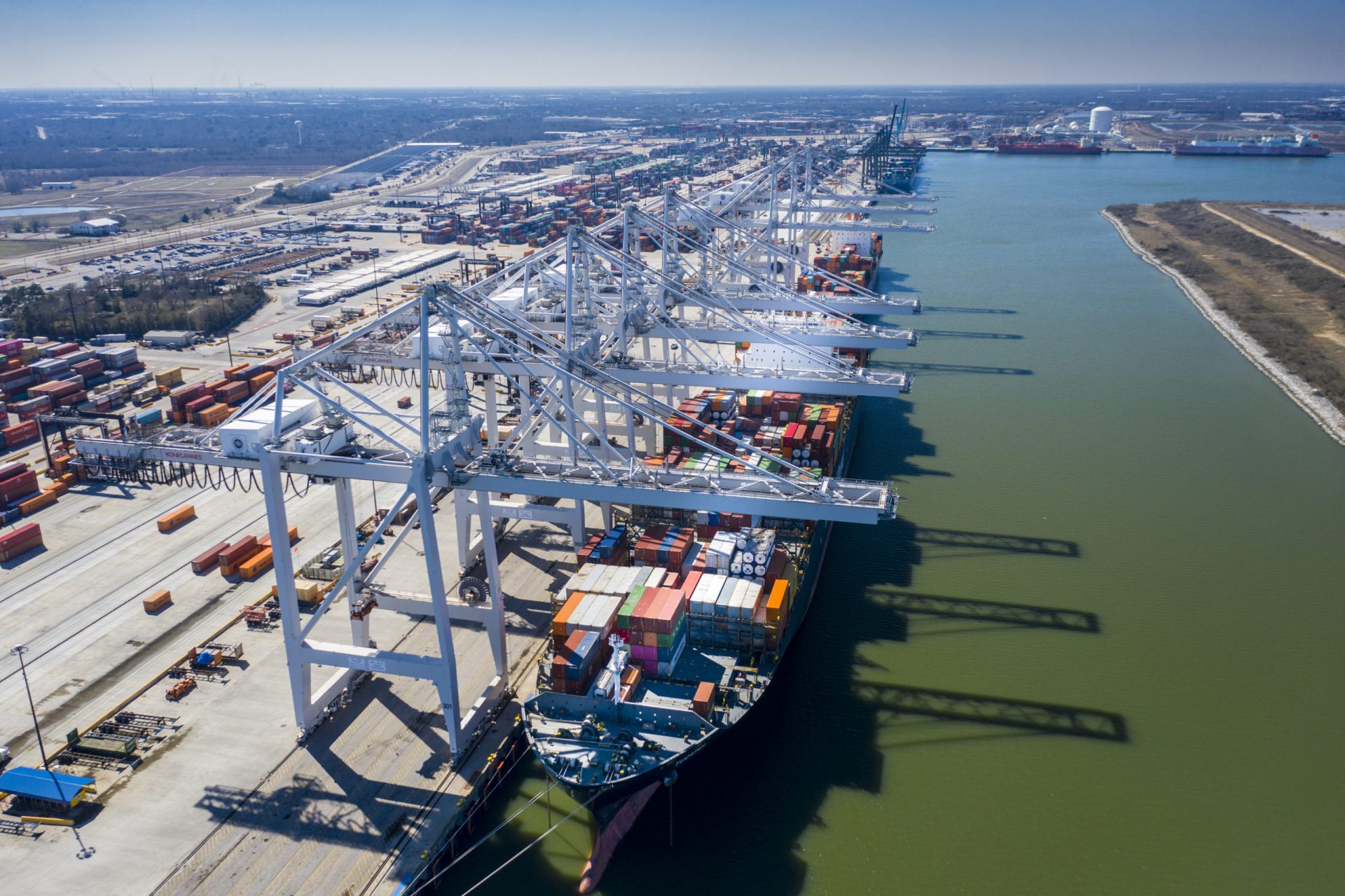 Aerial view of a busy shipping port of Houston with cargo ships, cranes, and containers.
