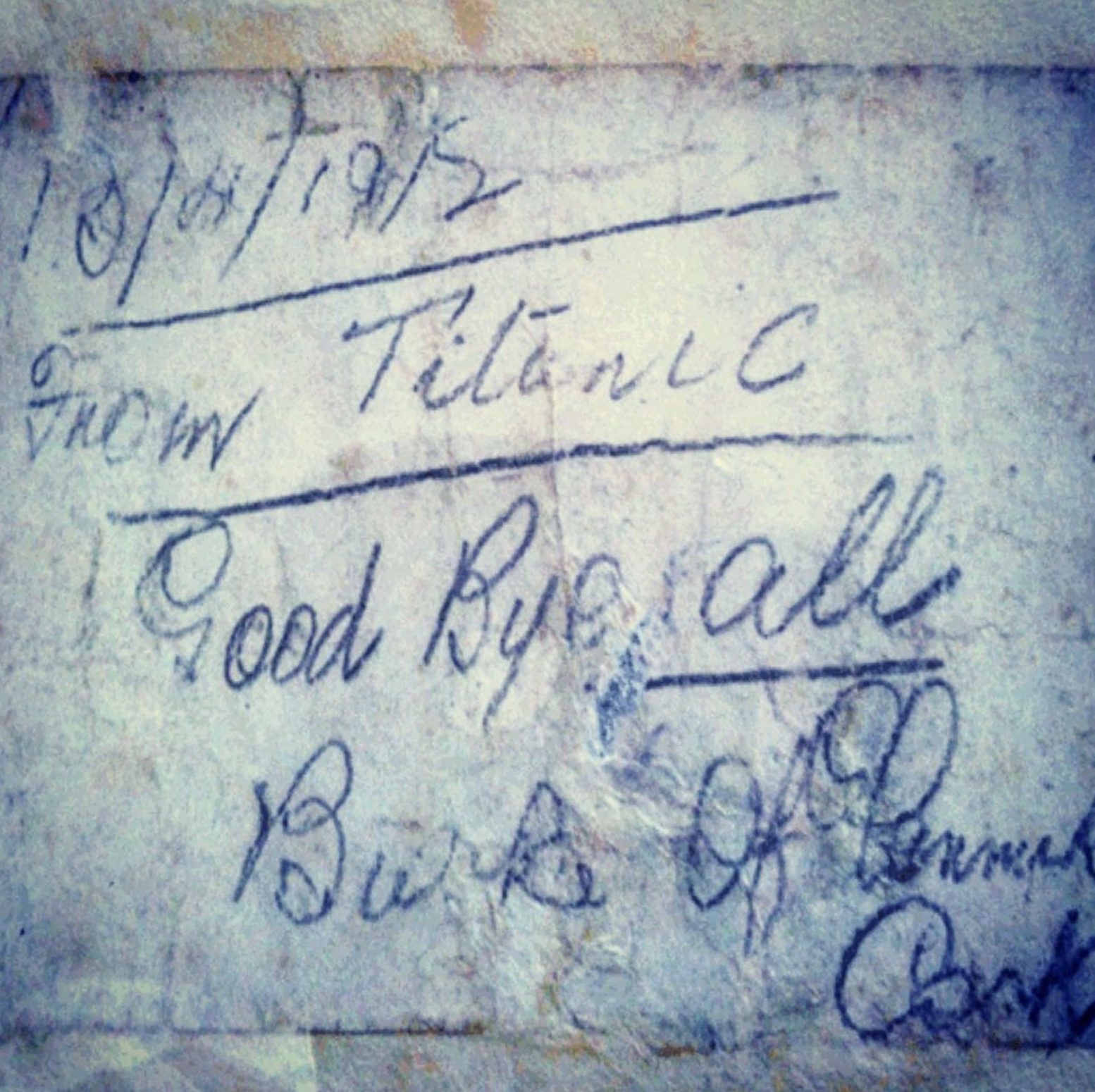 A photograph of a faded out note written in dark ink, the note says: From Titanic, Good Bye all. The note is signed Jeremiah Burke.