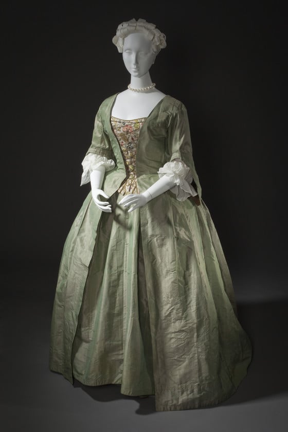 A photograph of a simple gray 17th century dress with a wide skirt, on a mannequin.