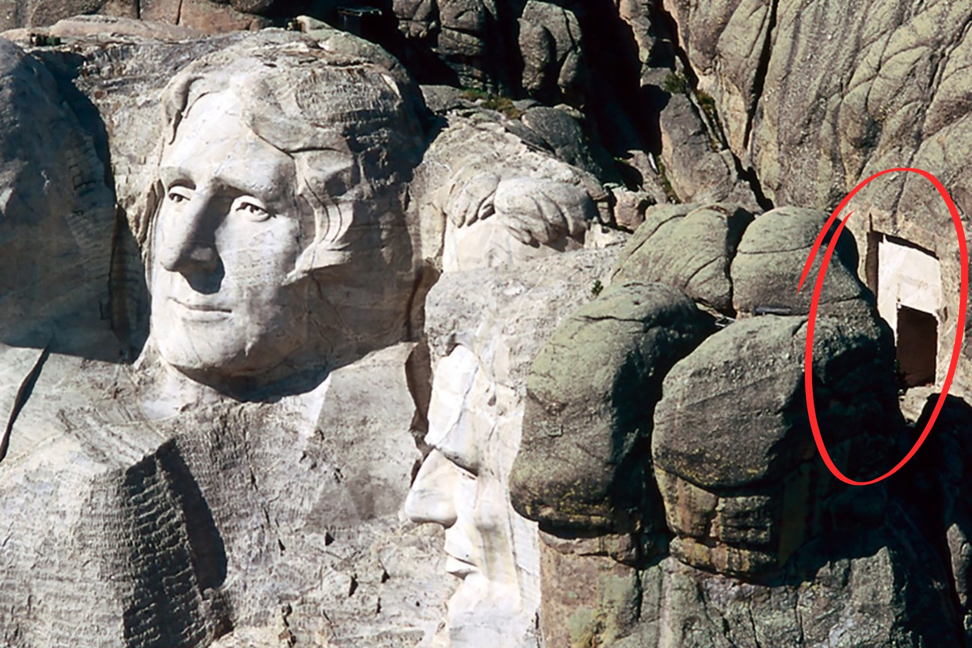 An arial photograph featuring the presidential heads at Mount Rushmore with a large rectangular opening carved into the rock behind the heads.