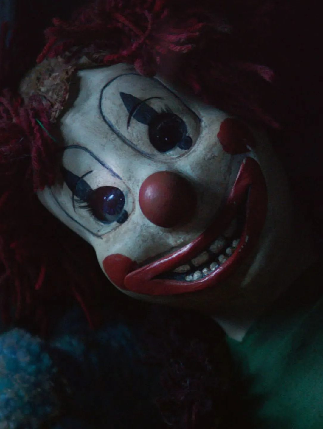 A creepy clown doll face with large red lips and a round red nose.