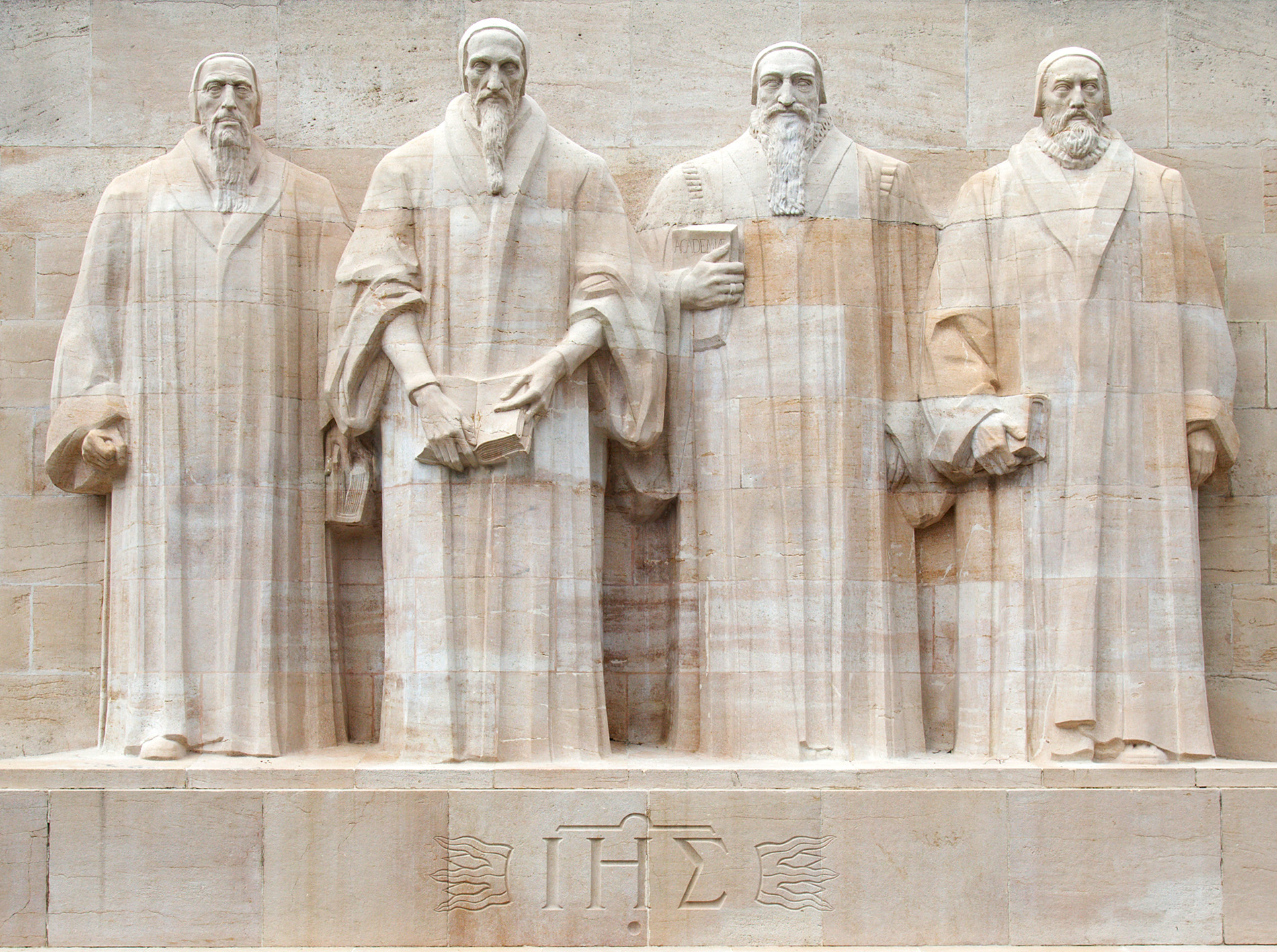 Reformation Monument located in Parc des Bastions, Geneva, Switzerland. The monument displays larger-than-life statues of four key figures of the Reformation, from left to right: William Farel, John Calvin, Theodore Beza, and John Knox. Each figure is carved in detailed relief, with books or scriptures in hand, symbolizing their significant contributions to religious reform.