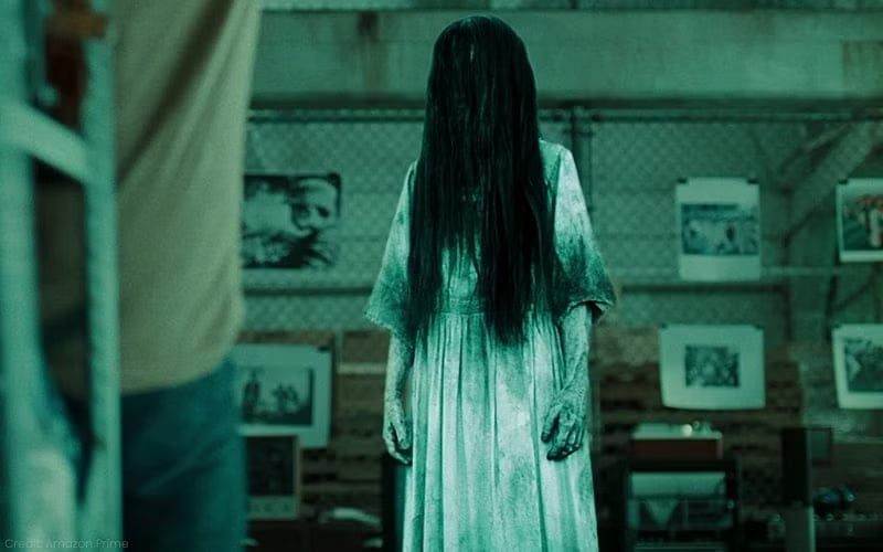 An image of a ghost in a dirty white dress, long black hair covering her face.
