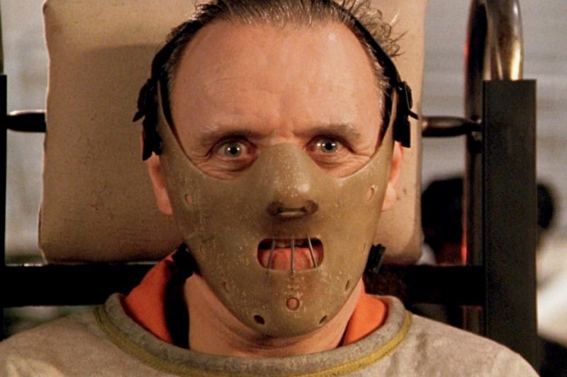A still shot of Hannibal Lecter from the movie Silence of the Lambs, wearing a mask and a straight jacket.