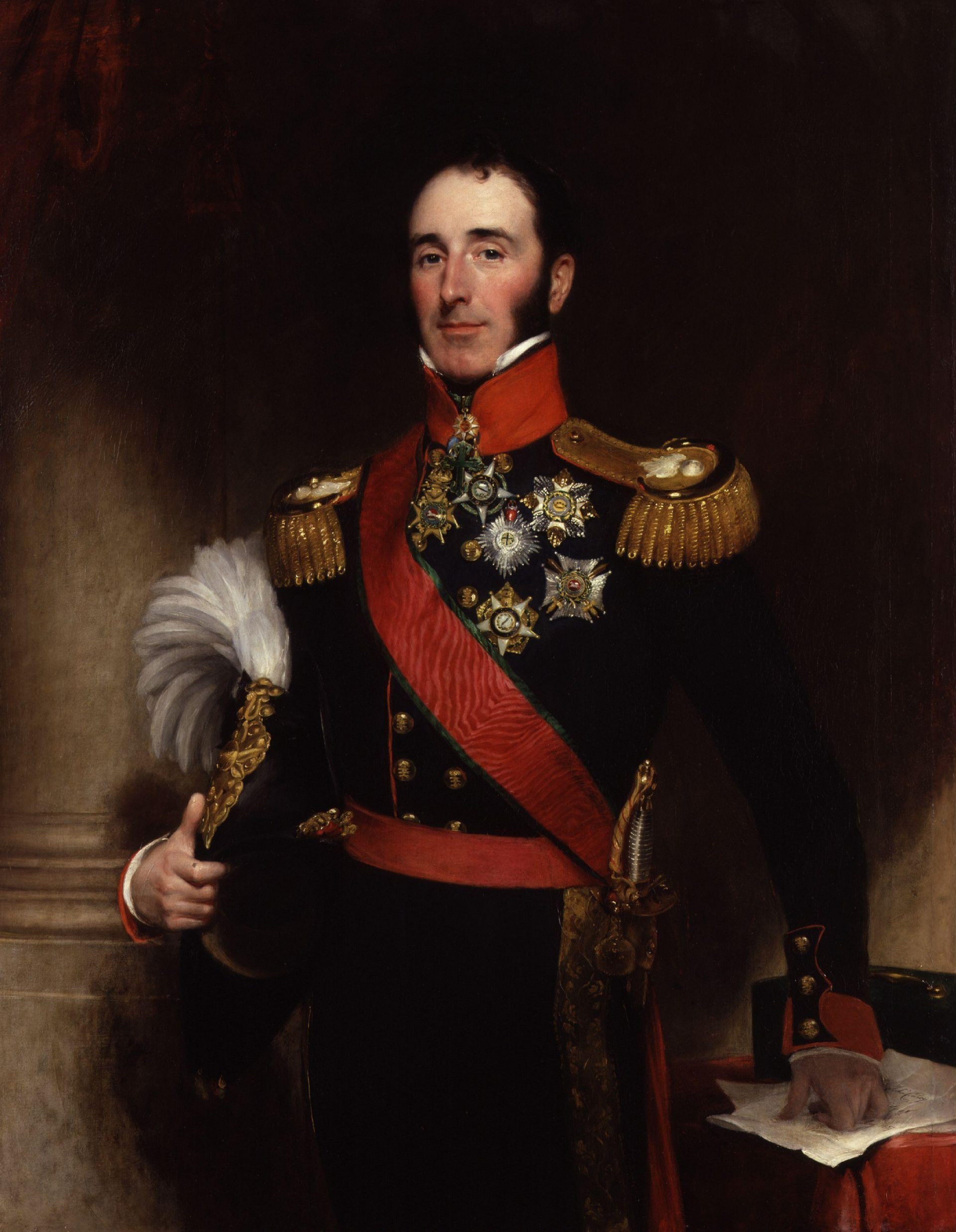 A portrait of Sir John Conroy, wearing a 19th century British military uniform. He is a man in his 30s with large sideburns. He is holding a hat with a feather under his arm. He has a sword attached to his side. His uniform is covered in medals.