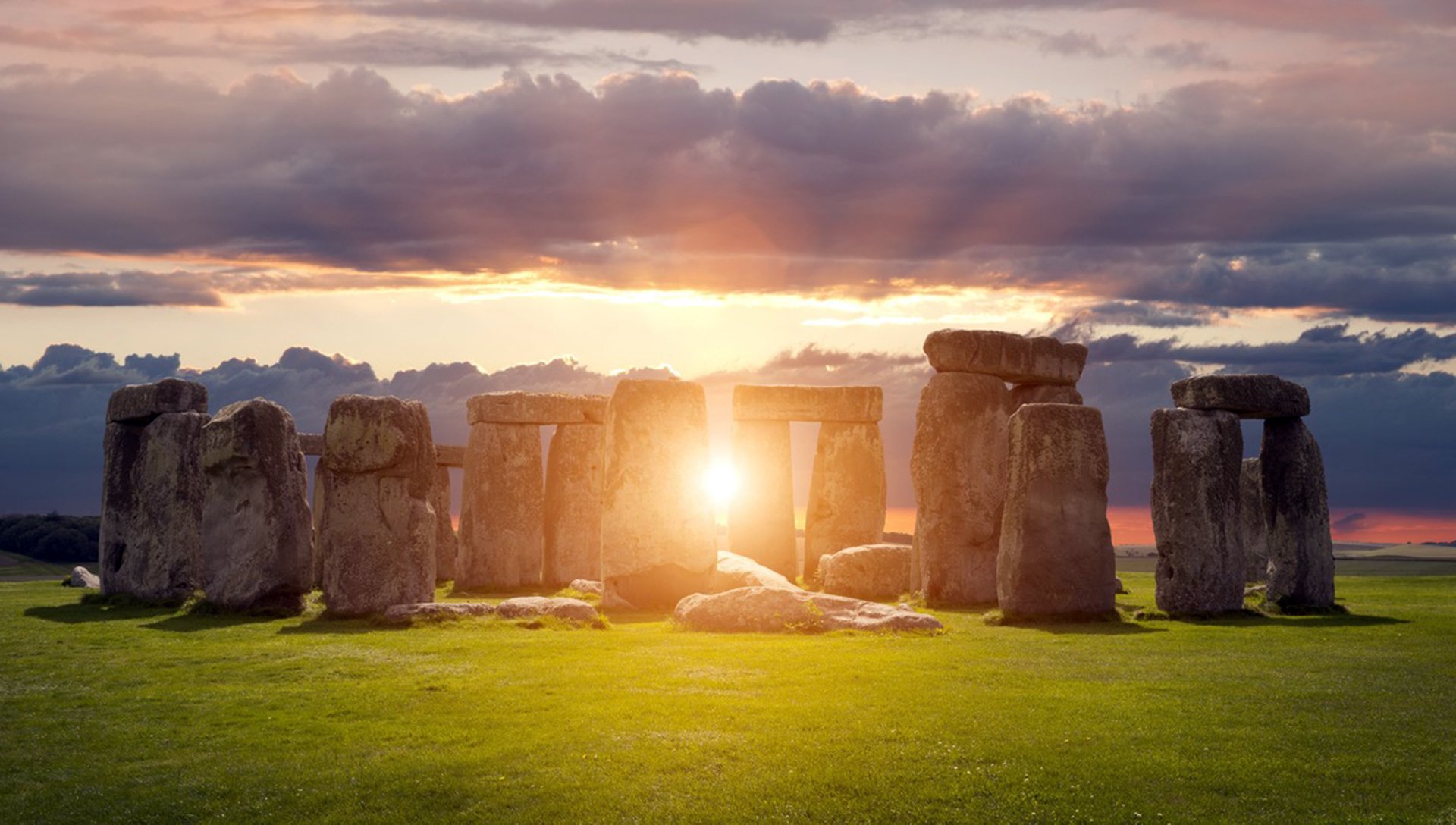 Stonehenge at sunset during the winter solstice, with the iconic stone structures silhouetted against a vibrant sky.