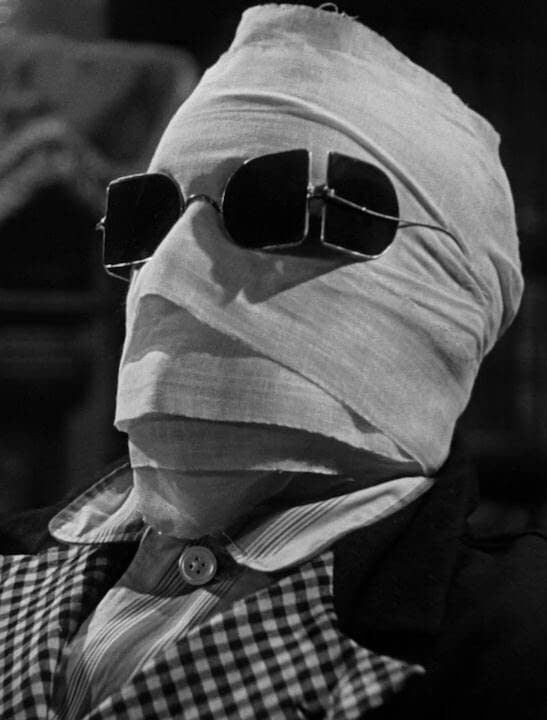A movie still of a man's face covered in bandages, wearing sunglasses.