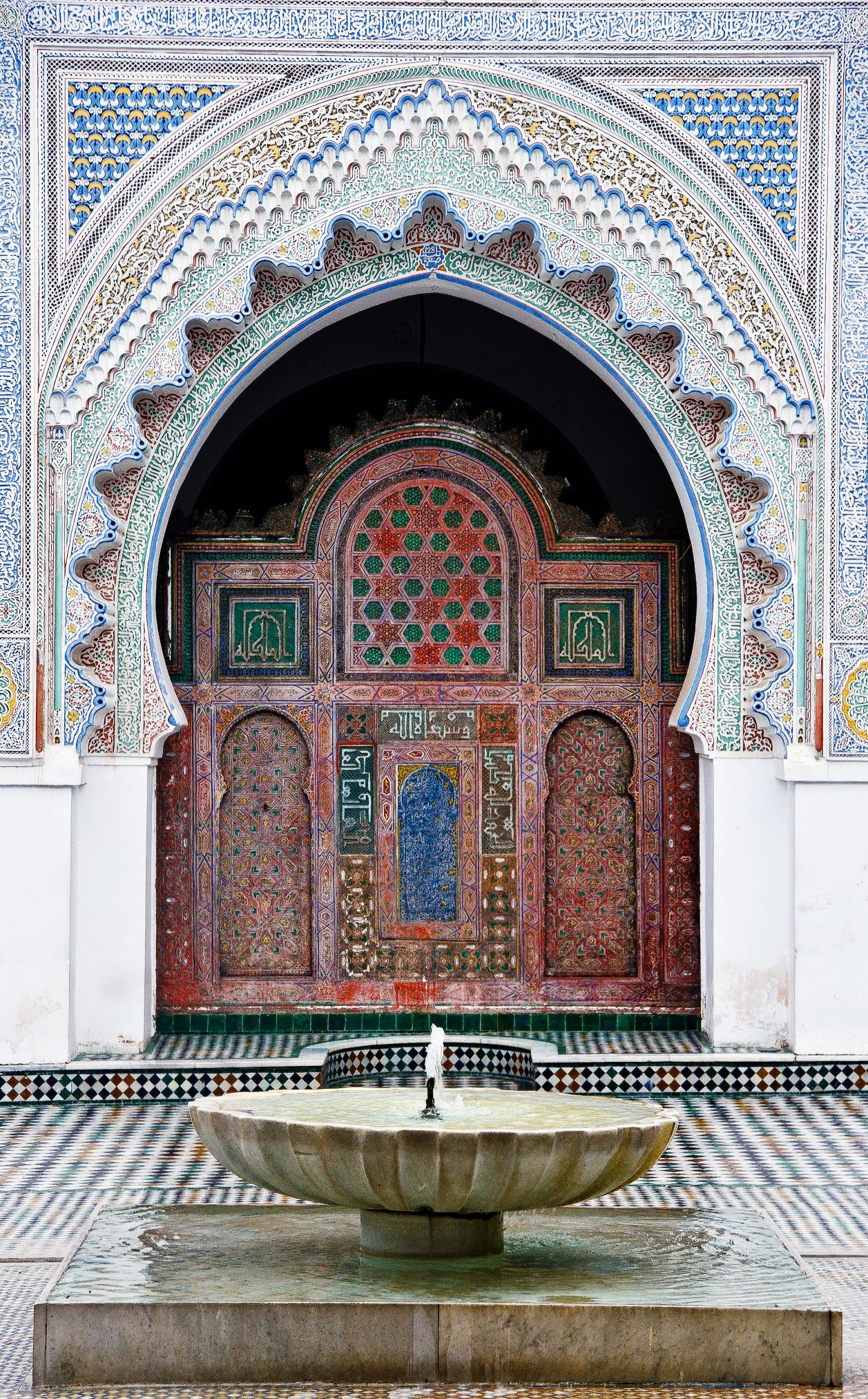 A Moroccan Courtyard of Al-Qarawiyyin University with a tiled archway and a fountain.