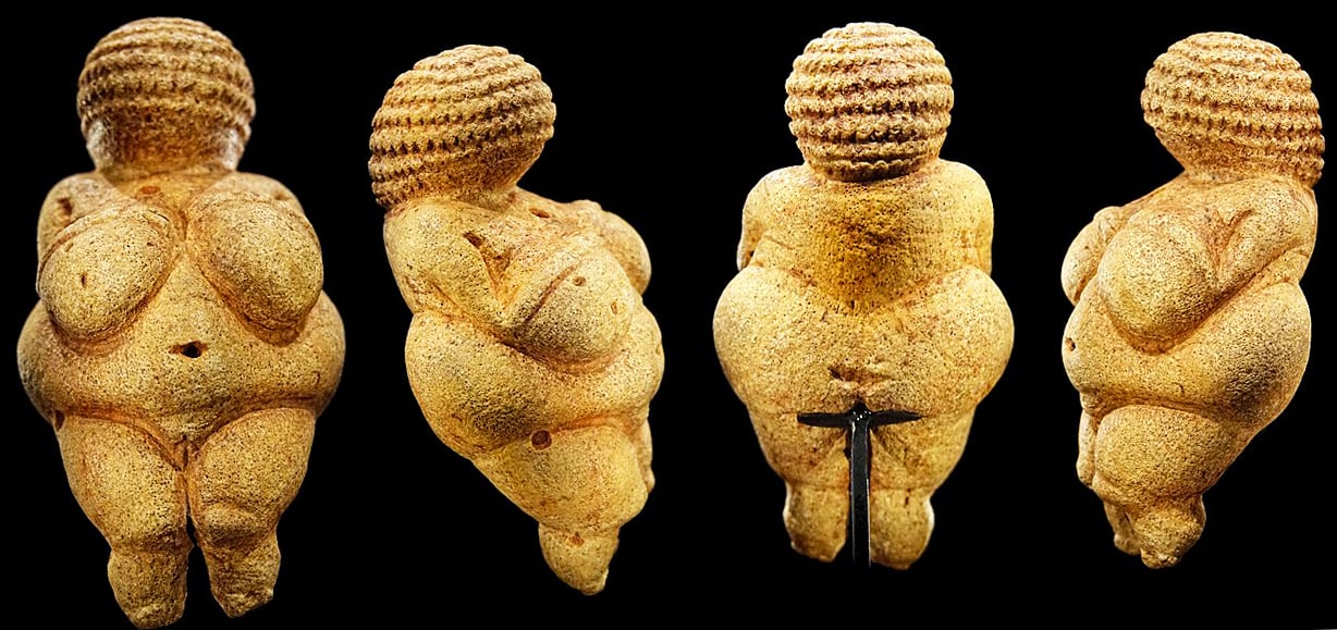 Four images of Venus of Willendorf, each facing a different direction, a light-colored statue of a woman with a large bust and hips and a high hairstyle, on a black surface.