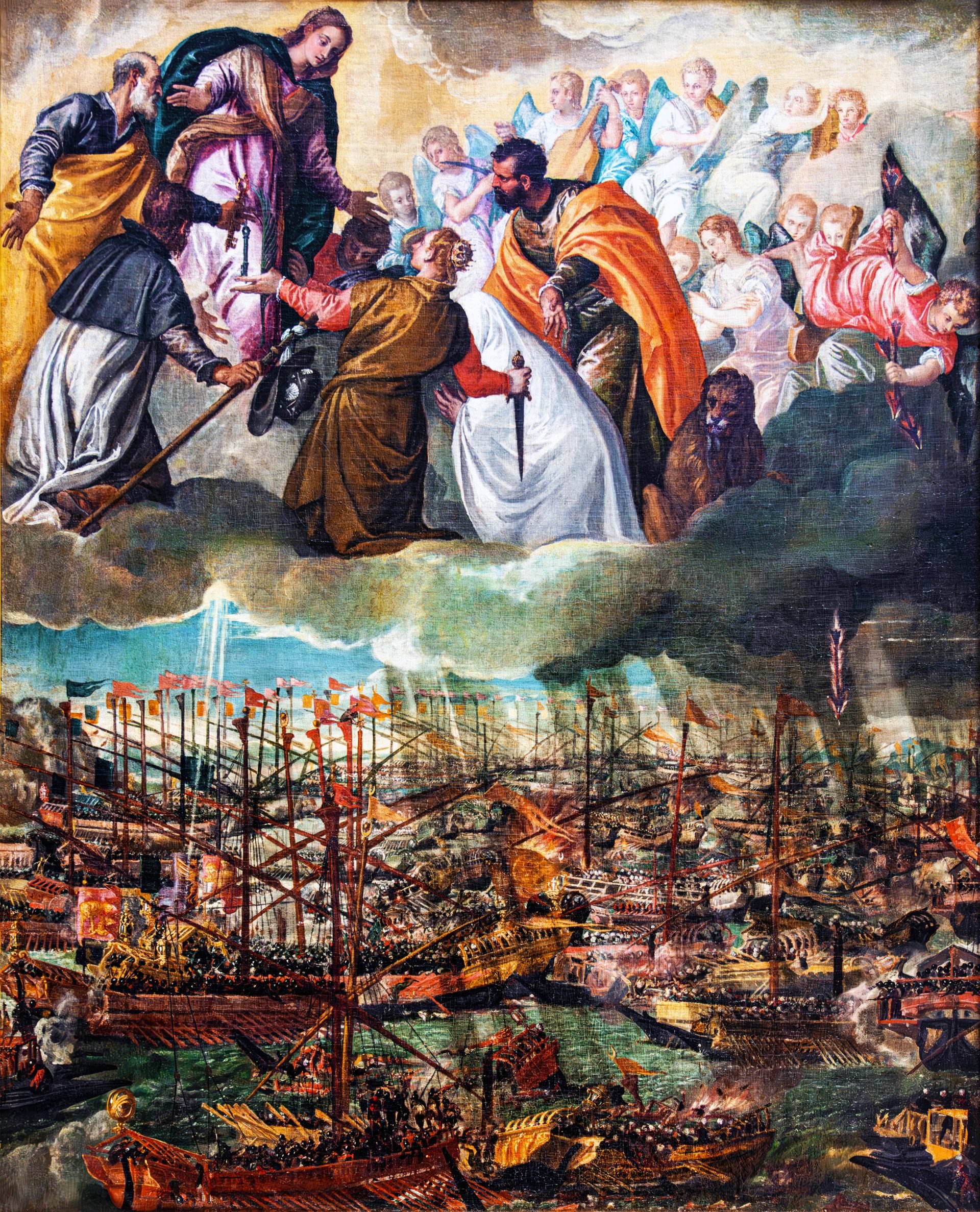 A vivid painting representing the Allegory of the Battle of Lepanto. The top half depicts celestial beings and saints, with a central figure of the Virgin Mary surrounded by angels, bestowing blessings upon Christian warriors below. St. Dominic, identifiable by his traditional habit, kneels in reverence, while other saintly figures are engaged in prayer or action. A looming, dark cloud separates the heavenly scene from the terrestrial below. The bottom half portrays a chaotic naval battle with numerous ships bearing flags, densely packed on a turbulent sea. Flames engulf some vessels, while plumes of smoke rise, indicating the intense warfare. The intricacies of the ships, from their masts to the combatants aboard, are intricately detailed, capturing the ferocity and significance of the Battle of Lepanto.