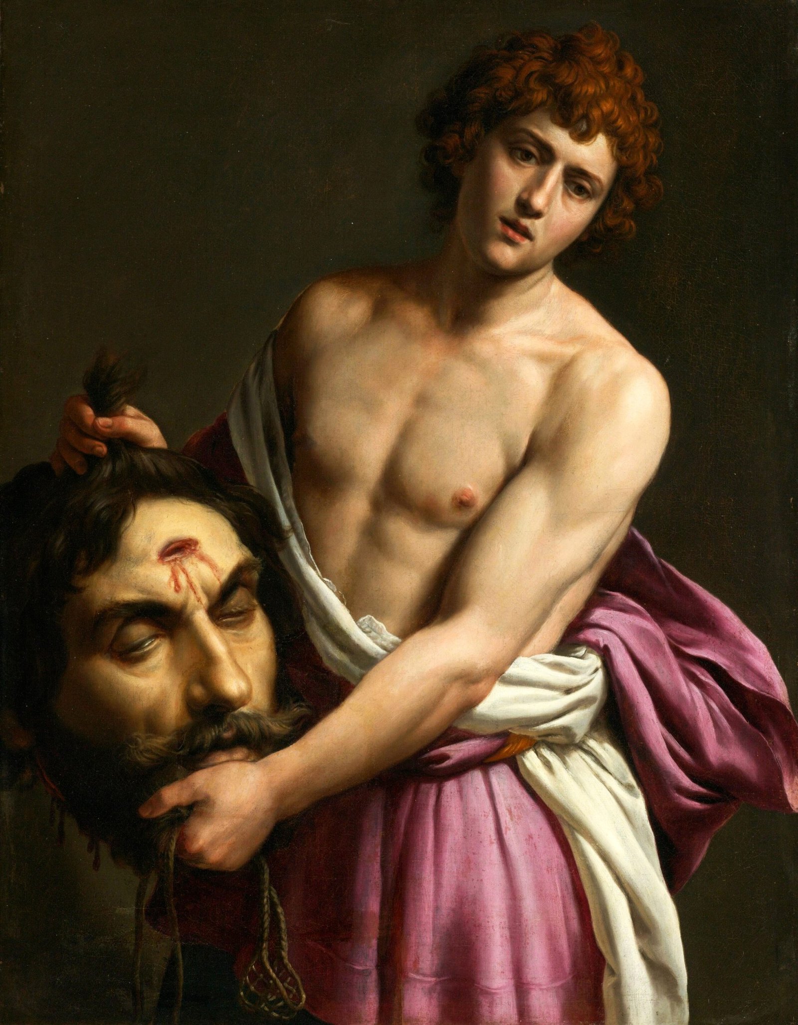 A painting from the 1620s by Alessandro Turchi depicting David, a young man with curly red hair and a contemplative expression, holding the severed head of Goliath. David is shown bare-chested, draped in a white cloth and a rich purple robe, while Goliath's head, with a dark beard and a prominent wound on the forehead, dangles from his grip. The background is dark, focusing the viewer's attention on the central figures and the stark contrast between David's youth and the lifeless visage of his foe.