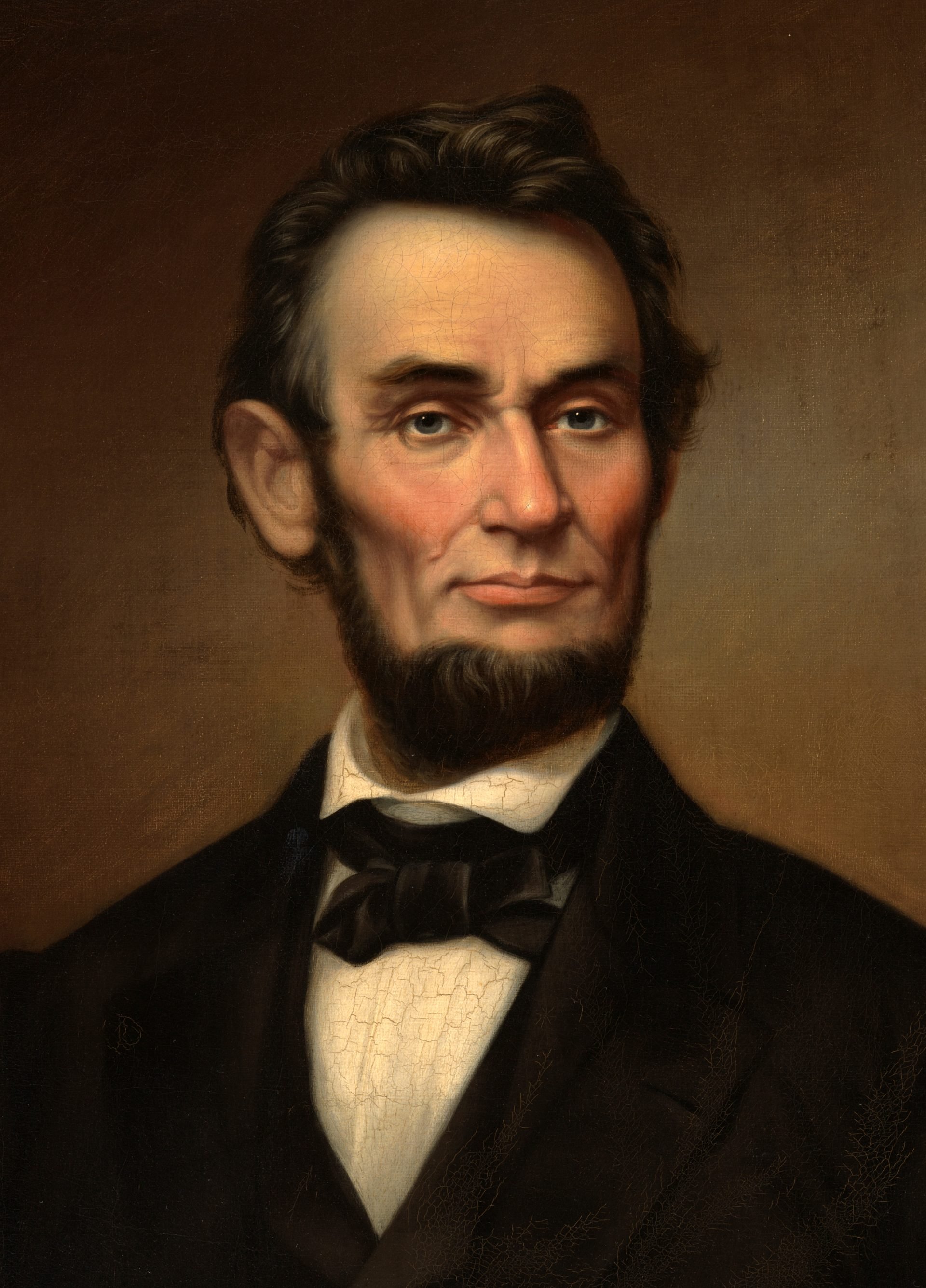 Portrait of Abraham Lincoln, painted by George Victor Cooper in 1865. Lincoln is depicted with a solemn expression, his dark hair combed to the side, and sporting his iconic beard without a mustache. He is dressed in a black suit with a bow tie and a white collared shirt. The painting has a plain brown background, and there are visible craquelure patterns across the canvas, indicative of the painting's age.