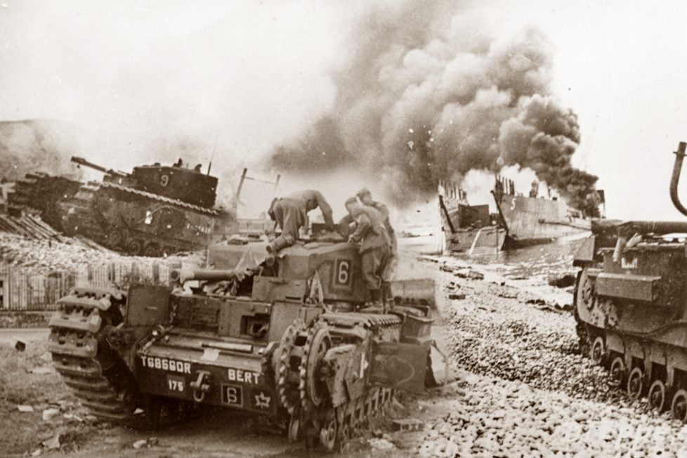 Sepia-toned historical photograph showing the chaotic scene of the Dieppe Raid with a "Churchill" tank marked with the number 6 in the foreground, and another tank number 9, amid smoke from a burning Landing Craft, Tank (LCT) in the background, illustrating the intense battle and strategic challenges faced during the operation.