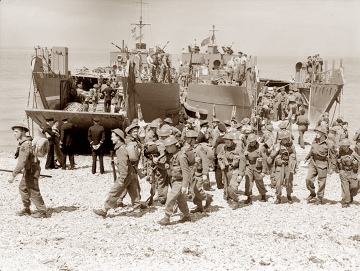  Image depicts a group of Canadian soldiers exiting a landing craft onto a pebble beach during a practice drill ahead of the historical Dieppe raid.