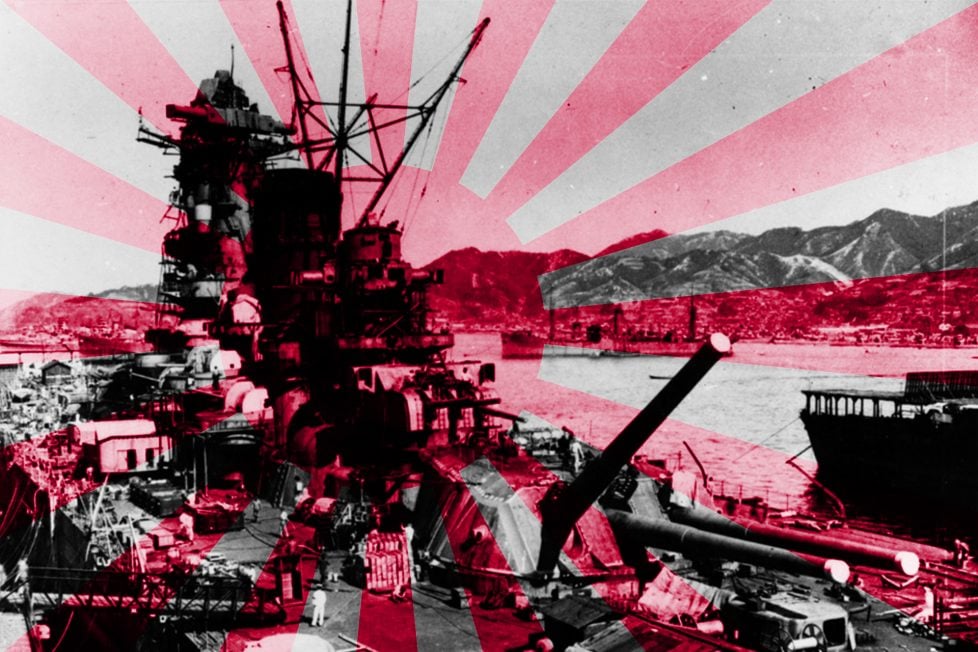 Historical photo of the battleship Yamato under construction, representing the "Kantai Kessen" strategy, with a dramatic red and white rising sun design in the background. Nearby ships and a hilly shoreline complete the scene, evoking the era of Japan's naval expansion.