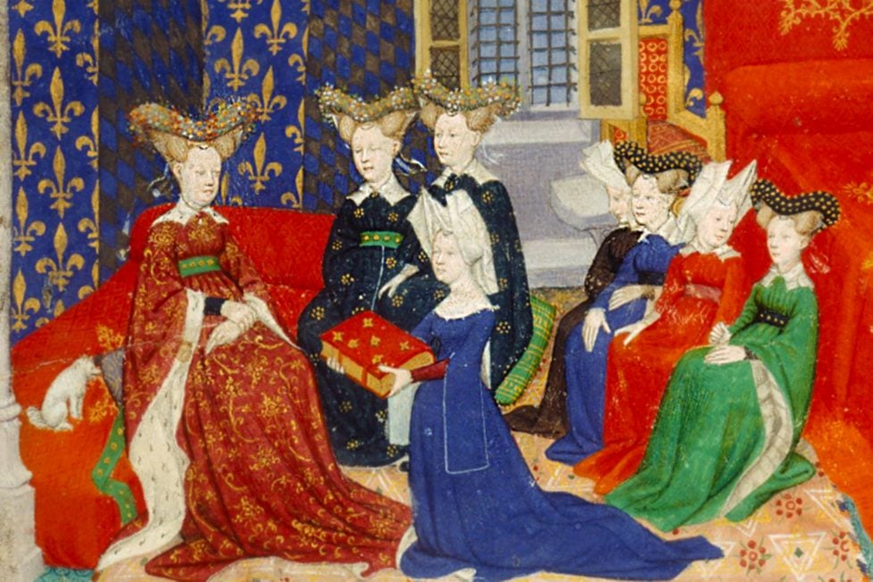 A detailed medieval painting depicting six women adorned in lavish dresses and headdresses, seated in an ornate chamber with patterned walls. The women are portrayed in various poses: some converse with each other, while one presents a decorated book. The vibrant colors of their garments, including deep reds, blues, and greens, are accentuated by intricate patterns and golden accents.