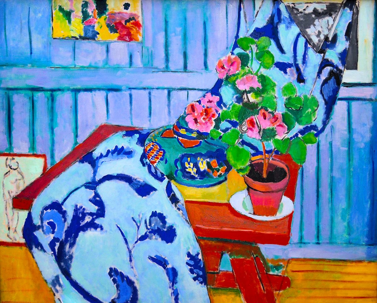 This image features Henri Matisse's 1910 painting "Still Life with Geraniums." The painting showcases a vibrant and colorful interior scene with a focus on a potted geranium plant. The geraniums, with lush green leaves and bright pink blooms, sit on a table covered with a decorative floral textile that twists through the painting's center. In the background, a blue wall is adorned with Matisse's own artwork, and the scene is completed with a detailed wooden floor and wall paneling. The use of color is bold and expressive, typical of Matisse's Fauvist period, with shades that don't conform to naturalistic colors, instead offering a more emotional and imaginative representation.